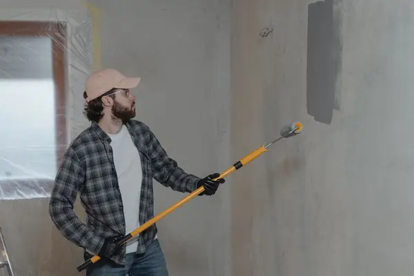 Painter rolling grey paint onto an interior wall in Salem